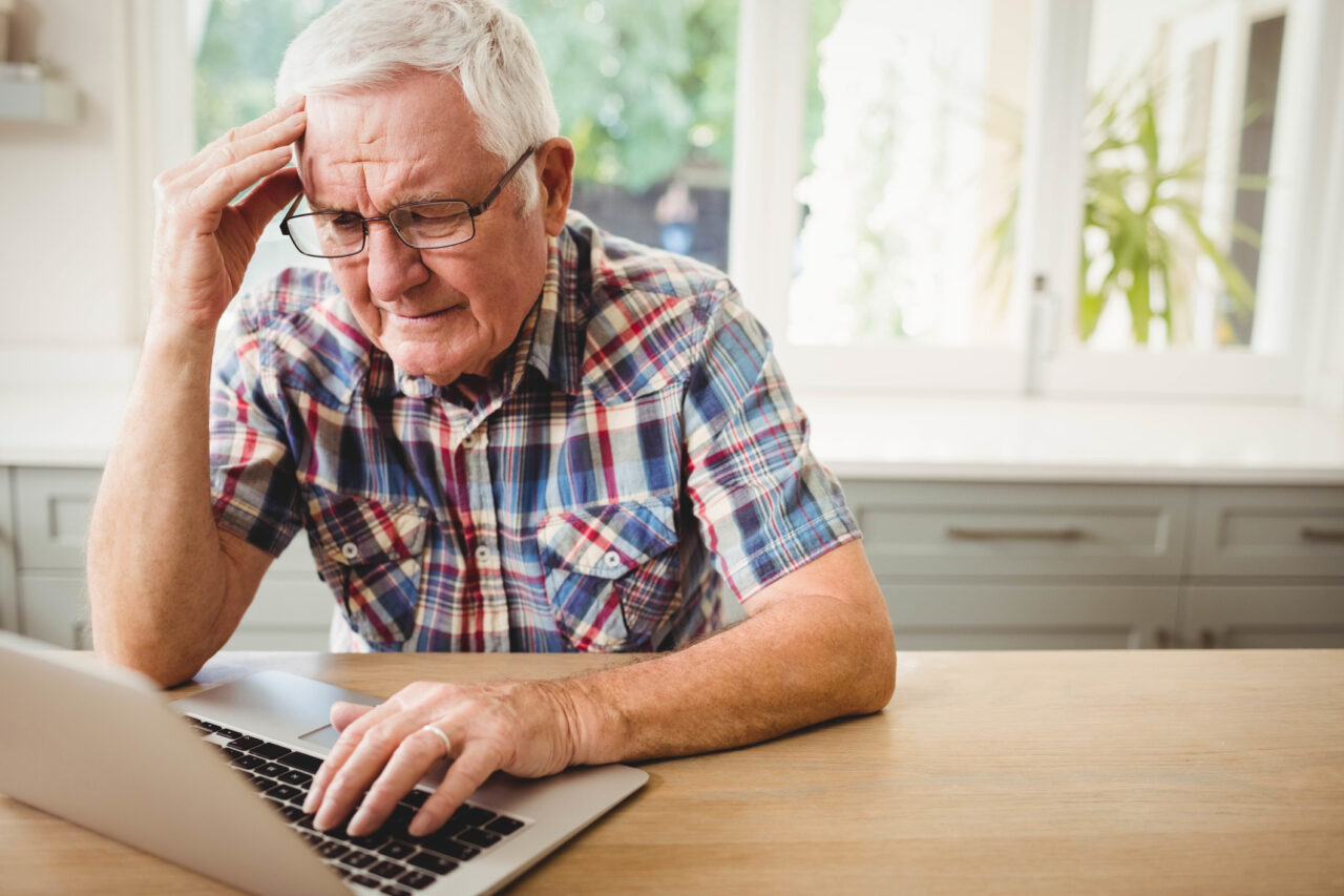 Older man at laptop looking distressed