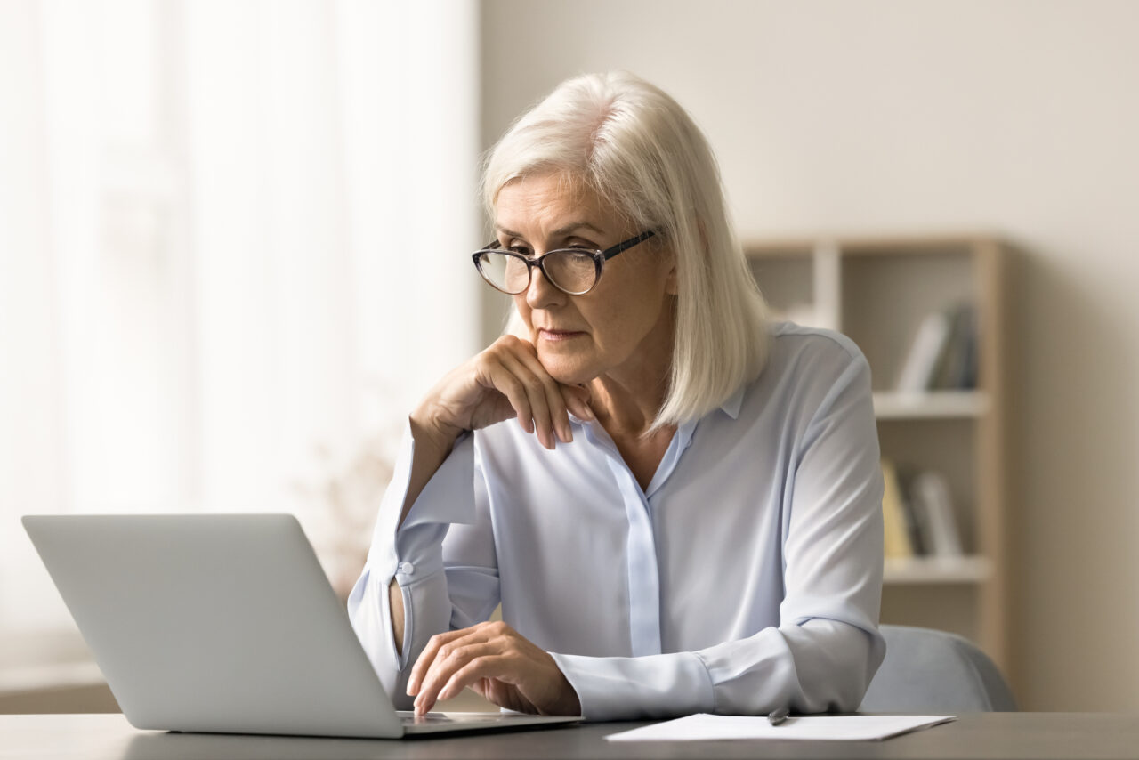 Older woman at desk using a laptop