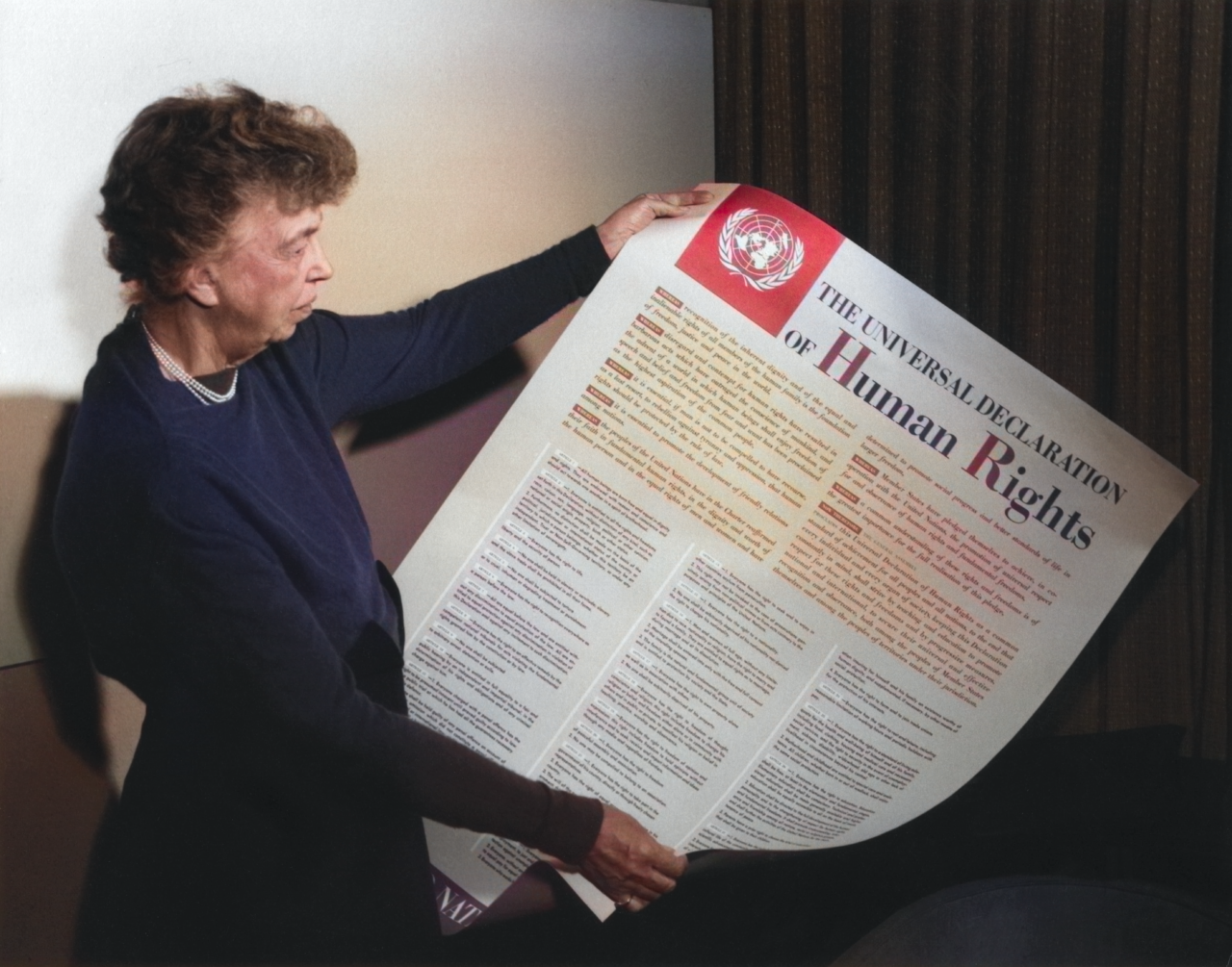 An older woman holding a large version of the Universal Declaration of Human Rights