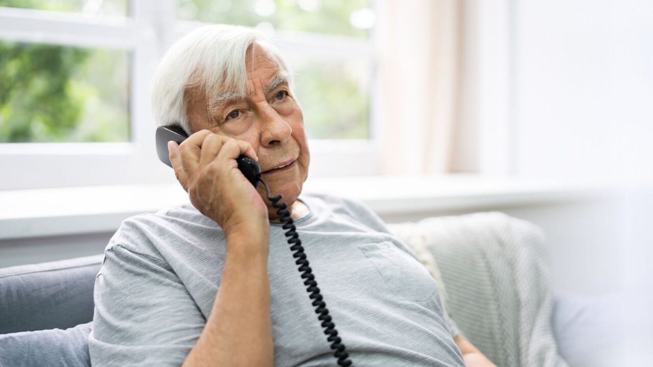Older man speaking on a landline telephone