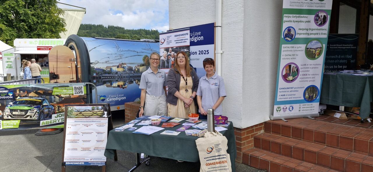 Roedd Comisiynydd Pobl Hŷn Cymru [dde], yn y llun ochr yn ochr â dau aelod arall o'r tîm, yn sefyll y tu ôl i'w bwrdd arddangos yn Sioe Amaethyddol Frenhinol Cymru.