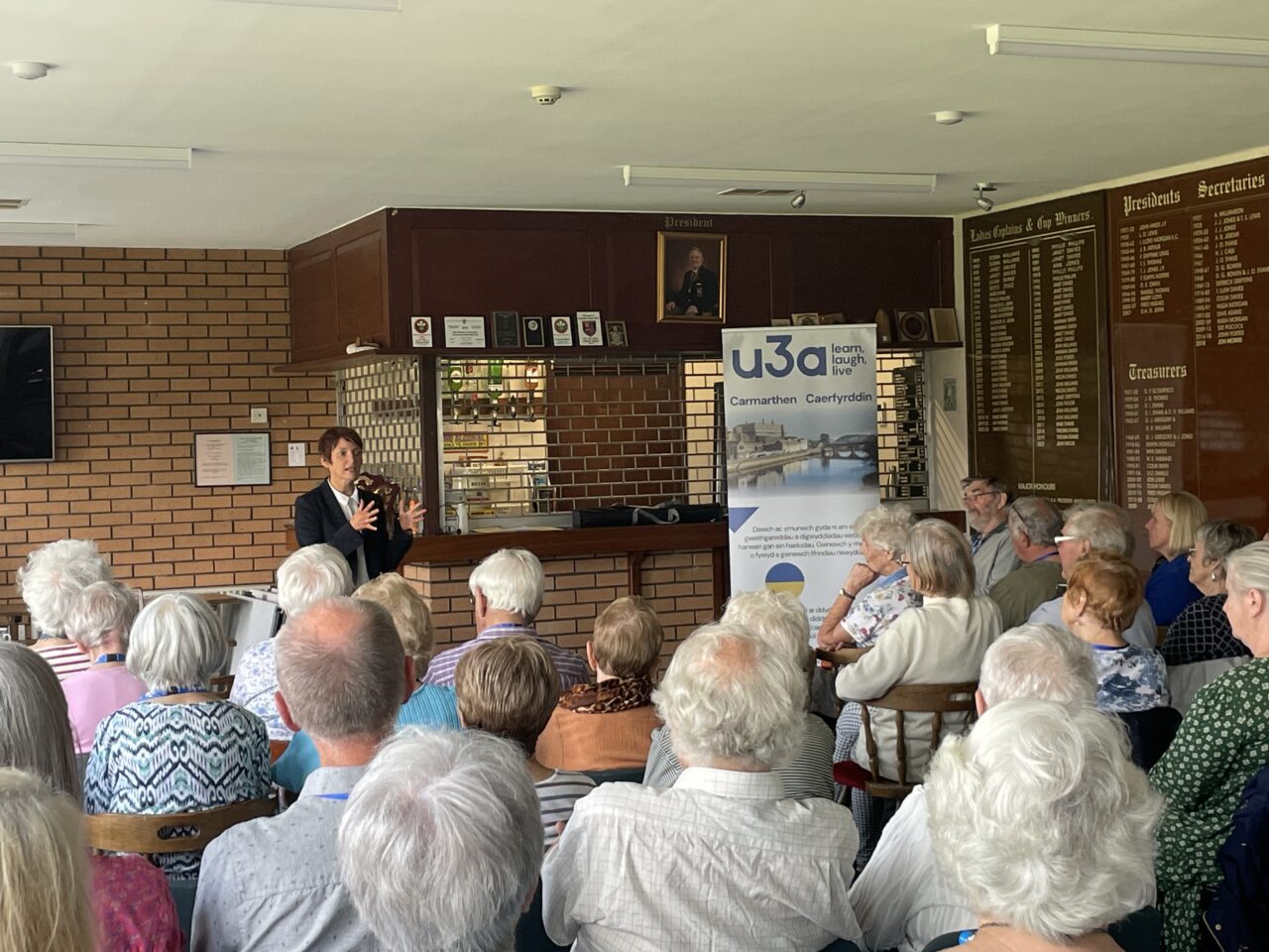 Around 50 members of Carmarthen's U3A are sat on chairs facing Rhian Bowen-Davies, who is giving a talk on her role.
