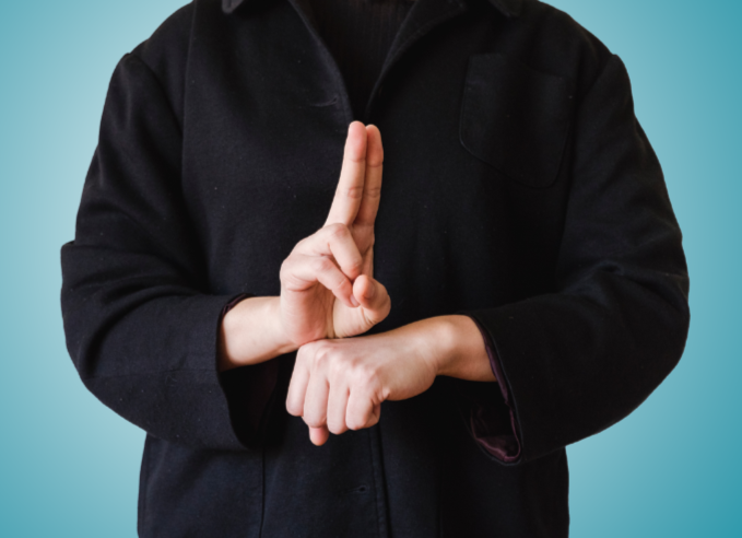 Person yn gwisgo du ac yn arwyddo gan ddefnyddio Iaith Arwyddion Prydain. // A person wearing black and signing using BSL.